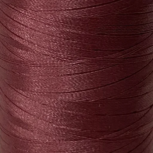 Bordeauxrood glanzend naai- of borduurgaren opgewikkeld op een klos in close-up