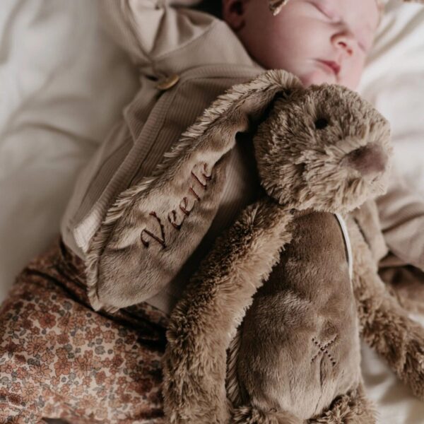 Baby slaapt met beige knuffelkonijn, geborduurd met de naam Veerle
